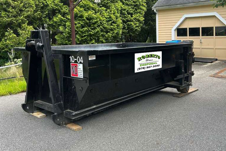 Black dumpster: About Roberto Brothers Disposal placed in a residential driveway.